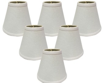 May include: Set of six white fabric lampshades with a simple, classic design. Each shade has a round, slightly flared shape and a smooth, white finish.