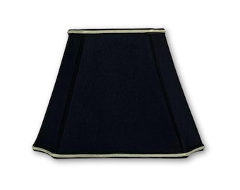 May include: A black lampshade with a white trim. The lampshade is square shaped and has a flat top.