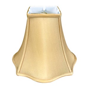 May include: A gold-colored lampshade with a scalloped edge. The shade is made of fabric and has a square top.