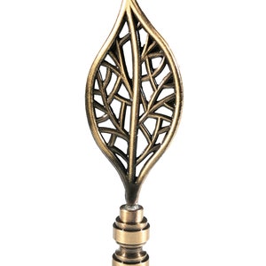 May include: A gold leaf-shaped finial with a detailed, intricate design. The finial is made of metal and has a traditional, ornate style.