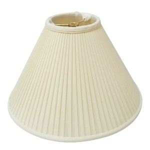 May include: A white pleated lampshade with a round shape and a brass finial.