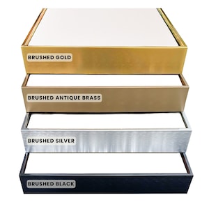 May include: Four different colored picture frames, stacked on top of each other. The frames are brushed gold, brushed antique brass, brushed silver, and brushed black.