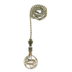 May include: A gold-toned metal light pull with a dragonfly design. The pull has a round, decorative top with two dragonflies in flight. The chain is made of small, round beads.