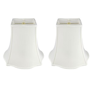 May include: Two white lampshades with a scalloped bottom edge. The lampshades are square at the top and have a bell shape.
