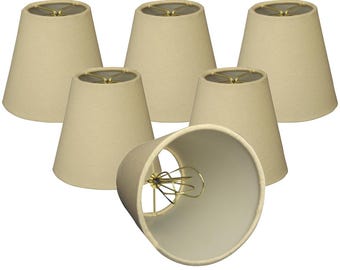 May include: Set of six off-white fabric lampshades with a simple, classic design. Each shade has a gold metal ring at the top.