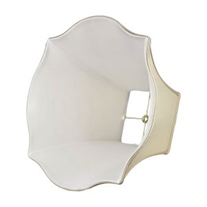 May include: A white lampshade with a scalloped edge and a gold trim. The lampshade is designed to fit over a standard lamp base.