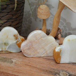 May include: Three white, brown and green onyx cloud-shaped sculptures. The sculptures are made of natural stone and have a unique, organic shape.
