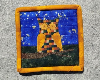 以下が含まれることがあります： 星空を背景に枝にとまるフクロウを描いた、正方形のキルト壁掛け。 フクロウは黄色い目とチェック柄の体をしている。 縁は黄色です。