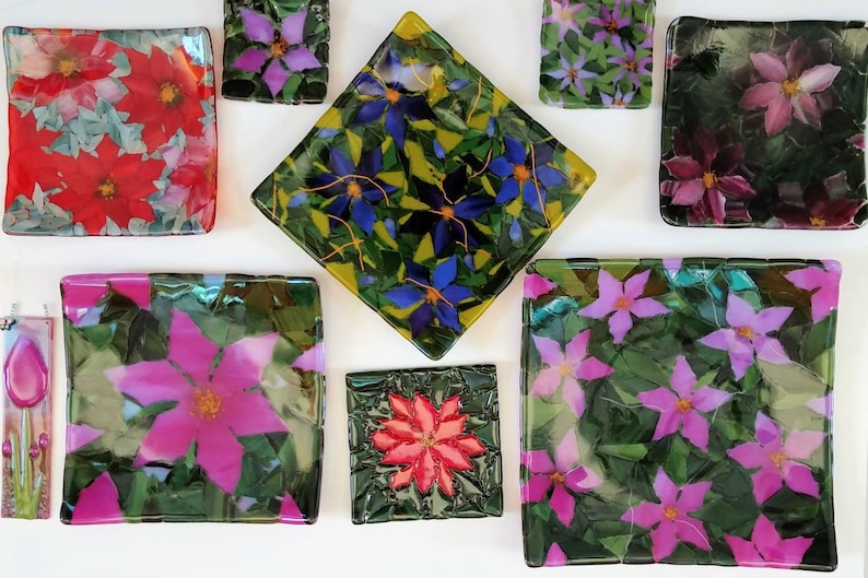 K&ouml;nnte beinhalten: Sortiment von neun quadratischen Glasplatten mit Blumendesigns. Die Platten zeigen verschiedene Farben, darunter Rot, Rosa, Lila, Blau und Gr&uuml;n. Die Designs sind Blumen mit aufwendigen Details.