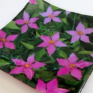 K&ouml;nnte beinhalten: Quadratische Glasplatte mit einem Mosaikdesign aus rosa Bl&uuml;ten und gr&uuml;nen Bl&auml;ttern.