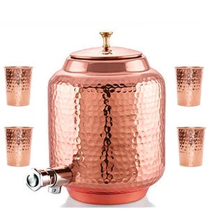 Peut inclure: Un distributeur d'eau en cuivre avec une texture martelée, un couvercle muni d'un petit bouton et un robinet en métal, accompagné de quatre gobelets en cuivre martelé assortis disposés autour du récipient central sur fond blanc.