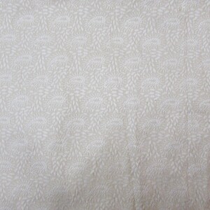 May include: Cream-colored fabric with a repeating pattern of stylized floral and leaf designs. The pattern is in a lighter shade of cream, creating a subtle contrast. The fabric appears to be a woven material.