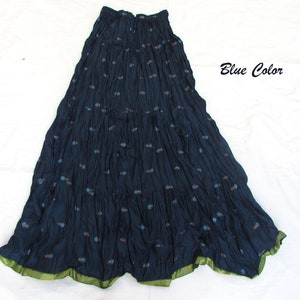 May include: A dark blue maxi skirt with a crinkled texture and a small floral pattern throughout. The skirt features an elasticized waistband and a contrasting green hem with a subtle dotted pattern. The text Blue Color is visible on the right.