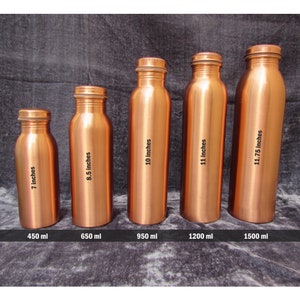May include: Five copper water bottles of varying sizes are displayed. The bottles range from 7 inches to 11.75 inches in height, with capacities from 450 ml to 1500 ml. Each bottle has a screw-on cap.