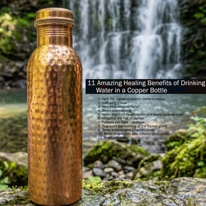 May include: A hammered copper water bottle with a cylindrical body and a matching screw-top lid. The bottle features text listing 11 Amazing Healing Benefits of Drinking Water in a Copper Bottle, including digestive health, weight loss, and skin health.
