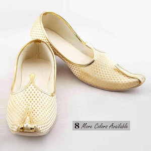 May include: A pair of cream-colored slip-on shoes featuring a repeating gold dot pattern, a pointed toe, and gold trim along the edges. The shoes have a low-profile design with a solid cream interior lining. The text 8 More Colors Available is visible.