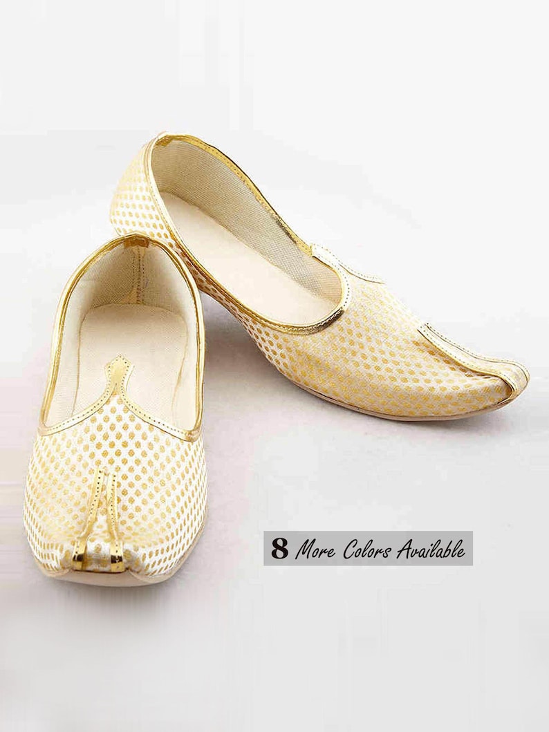 May include: A pair of cream-colored slip-on shoes featuring a repeating gold dot pattern, a pointed toe, and gold trim along the edges. The shoes have a low-profile design with a solid cream interior lining. The text 8 More Colors Available is visible.