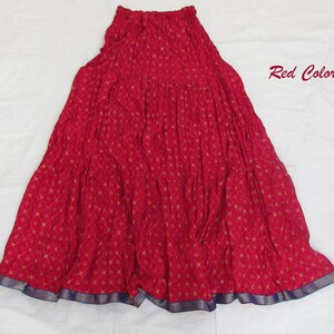 May include: A red tiered skirt featuring a repeating gold diamond and floral pattern, an elasticized waistband, and a dark blue border at the hem. The text Red Color is printed in the upper right corner of the image.