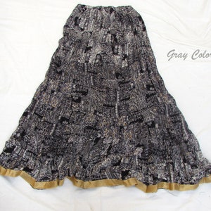 May include: A long, tiered skirt featuring a black, white, and gray patterned print with a gathered elastic waistband. The hem is finished with a solid gold-colored border. The text "Gray Color" is printed in the upper right corner of the image.