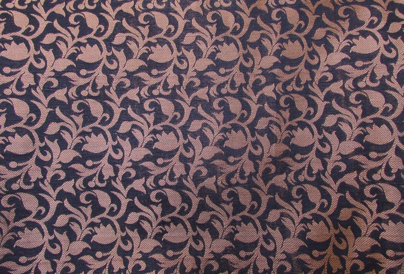 May include: A woven fabric featuring a repeating pattern of dark navy blue and light pink floral motifs. The design consists of intricate, swirling leaf and petal shapes that are densely packed across the entire surface of the textile material.