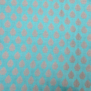 May include: A vibrant turquoise fabric featuring a repeating pattern of small, metallic silver leaf-shaped motifs arranged in a structured grid. The textile displays a visible woven texture with a consistent, uniform design across the entire surface.