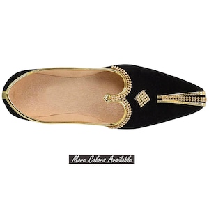 May include: A black slip-on shoe with a pointed toe, featuring gold metallic trim along the collar and a decorative gold embellishment on the vamp. The interior is lined in a light beige material. The text "More Colors Available" is visible.