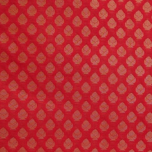 May include: Red fabric with a repeating pattern of stylized, gold-colored floral motifs. The design is evenly spaced across the surface, creating a textured appearance. The fabric has a slight sheen, enhancing the visual appeal.