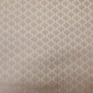 May include: A close-up of a fabric with a repeating pattern of stylized floral shapes in a light beige color. The pattern is set against a lighter, off-white background, creating a subtle contrast and texture.