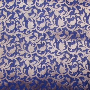 May include: A deep blue fabric featuring a repeating woven pattern of light beige floral and leaf motifs. The design consists of stylized tulip-like shapes and swirling vines that create a dense, intricate texture across the entire surface.