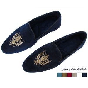 Pode incluir: Um par de chinelos de veludo azul-marinho com motivos bordados a dourado de abacaxi e flores no peito do p&eacute;. Os chinelos t&ecirc;m um rebordo escuro na abertura e o texto 7 More Colors Available com seis pequenos quadrados coloridos.