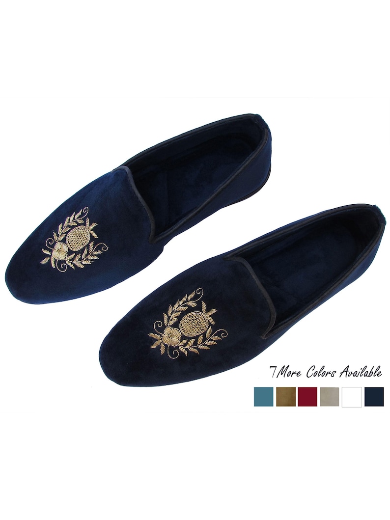 Pode incluir: Um par de chinelos de veludo azul-marinho com motivos bordados a dourado de abacaxi e flores no peito do p&eacute;. Os chinelos t&ecirc;m um rebordo escuro na abertura e o texto 7 More Colors Available com seis pequenos quadrados coloridos.