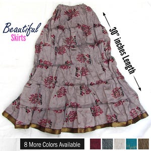 Puede incluir: Una falda de niveles en color malva claro con un patrón floral repetitivo en rojo y negro. La falda tiene un borde metálico dorado a lo largo del dobladillo inferior y una longitud de 76,2 cm. El texto dice Beautiful Skirts y 30 inches Length.