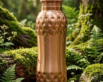 Könnte beinhalten: Eine metallische Kupfer-Wasserflasche mit zylindrischer Form, die ein texturiertes Grübchenmuster an den oberen und unteren Abschnitten, ein glattes Mittelband und einen Schraubverschluss aufweist, mit kleinen Wassertropfen auf der Oberfläche.