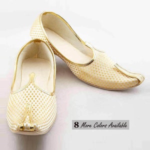 May include: A pair of slip-on shoes featuring a cream-colored fabric base with a repeating gold dot pattern. The shoes have a pointed toe, a gold-trimmed collar, and a low-profile design. A small rectangular graphic states 8 More Colors Available.