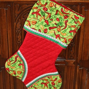 May include: Red and green Christmas stocking with a quilted red body and a green and white fabric cuff featuring a pattern of red chili peppers.