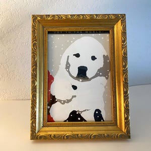 May include: A framed print featuring a snowman illustration with the text "JOY TO THE WORLD!". The frame is gold-colored with ornate detailing. The snowman is white with black accents, set against a snowy gray background.