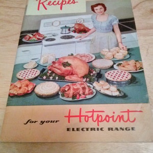 May include: A vintage cookbook with a red "Recipes" title and a woman in a blue dress standing in front of a white stove. The cookbook is for a Hotpoint Electric Range and features a variety of food items, including a turkey, pies, and pastries.