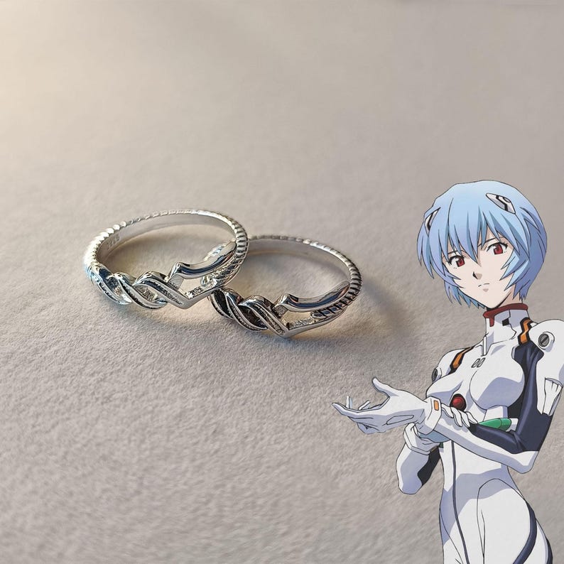 May include: Two silver rings with an intricate, interwoven design. The rings are displayed on a neutral surface. The design features a series of curved lines and geometric shapes, creating a visually appealing pattern.