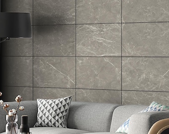 May include: A living room interior with a gray couch, a black and brown armchair, a black coffee table, and a gray marble wall.