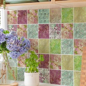 Puede incluir: Un salpicadero de cocina con una cuadrícula de azulejos cuadrados que presentan una mezcla de patrones florales y de estilo vintage en tonos verdes, morados y crema. Los azulejos están dispuestos en un patrón uniforme sobre una encimera blanca.