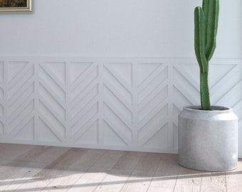 May include: A framed painting of a woman's face with gold accents hangs on a white wall with white wainscoting. A potted cactus plant sits on the floor to the right of the painting.