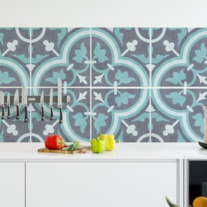 May include: A kitchen backsplash featuring square tiles with a repeating pattern in shades of dark gray, light blue, and white. A magnetic knife strip holds five stainless steel knives, while a wooden cutting board and fresh produce sit below.