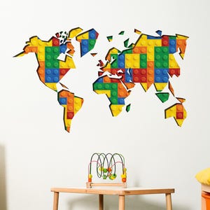Puede incluir: Un colorido mapa del mundo hecho con bloques de juguete está montado en una pared blanca. El mapa está compuesto por bloques amarillos, verdes, azules y rojos. Una pequeña mesa y taburetes de madera están sobre una alfombra verde.