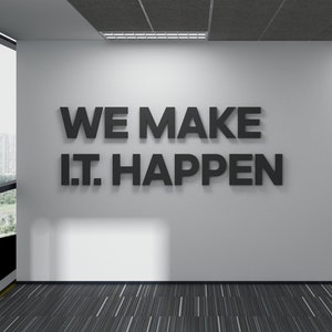 May include: A white wall with the text "WE MAKE IT HAPPEN" in black 3D letters. The wall is in an office setting with a carpeted floor and a window in the background.