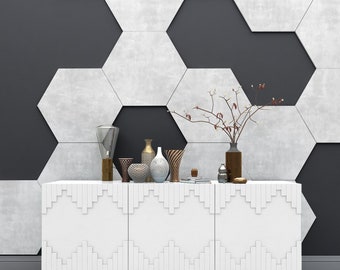 Può includere: Un mobile bianco con tre ante e un motivo geometrico. Il mobile è decorato con vasi, una lampada e una piccola pianta. Il mobile è davanti a un muro con un motivo esagonale.