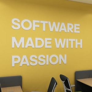 Puede incluir: Una pared amarilla con el texto "SOFTWARE MADE WITH PASSION" en letras blancas. Dos sillas de oficina negras con cojines verdes están en primer plano.
