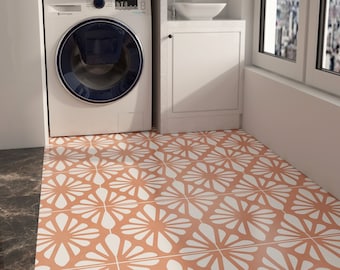 Può includere: Una lavatrice bianca con un cestello blu, un piano di lavoro bianco con un piccolo lavandino e un armadio bianco con una porta. Il pavimento è piastrellato con un motivo geometrico in tonalità arancio e bianco.