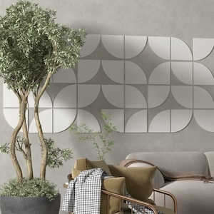 Puede incluir: Un diseño de interior de sala de estar con una pared gris que presenta un patrón geométrico de semicírculos blancos. Un sillón marrón con una manta de tiro blanco y negro se encuentra frente a un sofá gris. Una planta verde en maceta está en la esquina de la habitación.