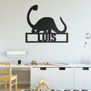 May include: Black dinosaur wall decor with the name "Luis" cut out below. The dinosaur is standing on a shelf with a white background.