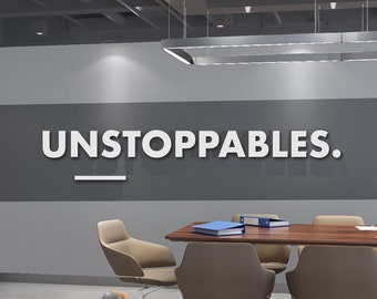 Może przedstawiać: Sala konferencyjna w biurze z dużym drewnianym stołem i kilkoma krzesłami. Na ścianie widnieje napis "UNSTOPPABLES." w białych literach. Pokój ma nowoczesny design z szarymi ścianami i betonową podłogą.